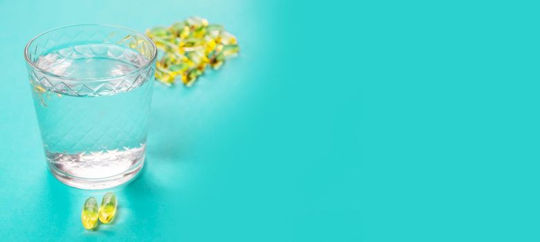 Omega 3 fish oil capsules spilling out of a bottle on a blue background.