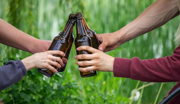 The hand of a man holding a beer bottle in nature. rest by the river. Nature. Selective focus