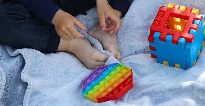 Pop it silicone anti-stress toy. The child plays on the grass. New trend Selective focus. Nature
