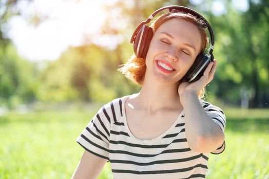 Young attractive woman listens to music in the park. Enjoying music in the park