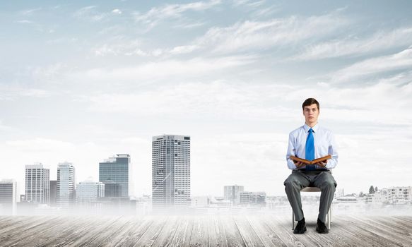 young businessman with book on office chair