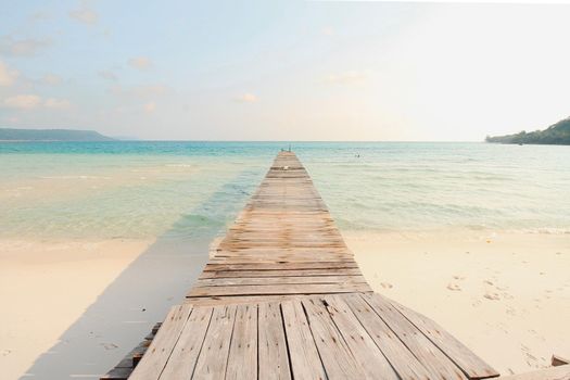 Scenic view of a wooden boardwalk leaving to the white sandy beach of Koh Rong Samloen Island, a popular summer getaway destination in Cambodia