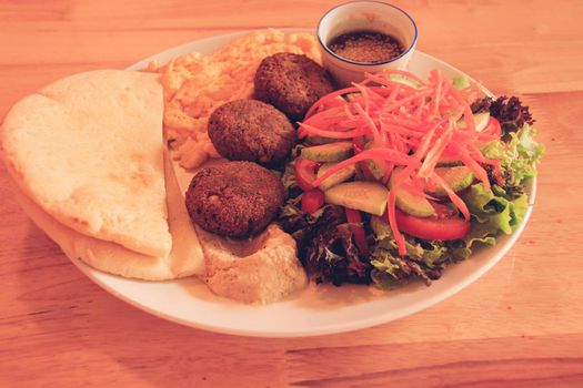 A plate full of falafel balls, pita bread, scrambled eggs and raw vegetable salad for a healthy high protein ovo-vegetarian ketogenic breakfast