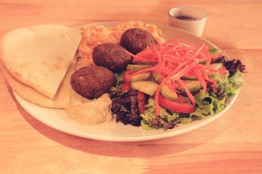 A plate full of falafel balls, pita bread, scrambled eggs and raw vegetable salad for a healthy high protein ovo-vegetarian ketogenic breakfast