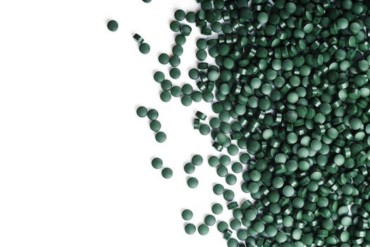 Vegetarian vitamins from Spirulina are scattered on a white background with free space