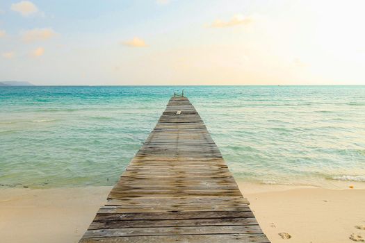 Scenic view of a wooden boardwalk leaving to the white sandy beach of Koh Rong Samloen Island, a popular summer getaway destination in Cambodia