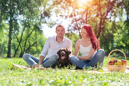 A couple and their dog in the park. Spending time with friends