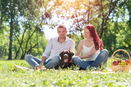 A couple and their dog in the park. Spending time with friends