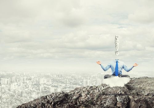 Businessman sitting in lotus pose and exclamation mark instead of his head