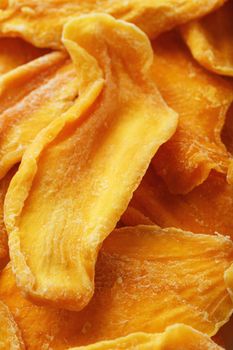 Dried sweet mango fruit slices as textural orange background in full screen