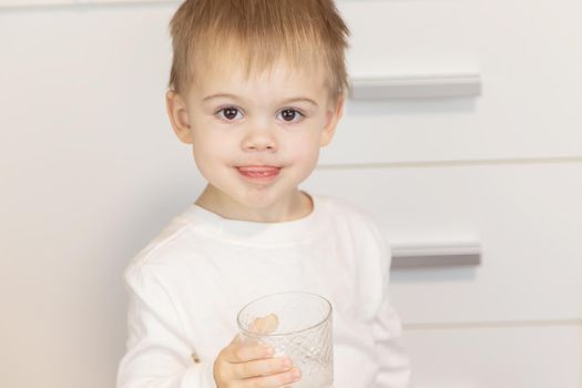 The child drinks water from a glass. Selective focus.