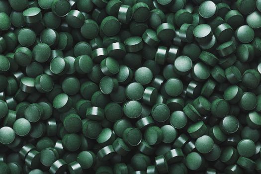 Dark Green round tablets of organic spirulina as a texture background in full screen