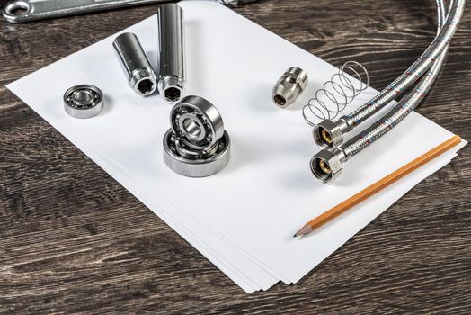 Plumbing pipeline and ball bearings laying on table. Water fittings and connections with segments of braided hose. Steel details for engine mechanisms. House infrastructure designing and installation