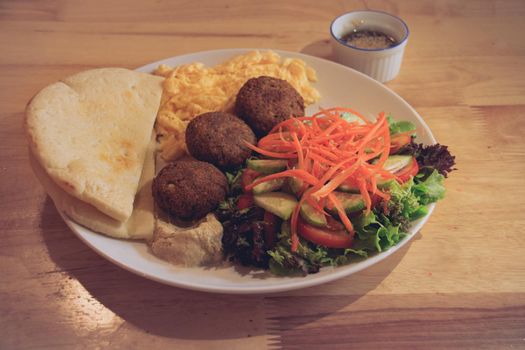 Pita bread, falafel, hummus, salad and scrambled eggs for a healthy modern middle eastern breakfast