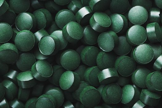 Dark Green round tablets of organic spirulina as a texture background in full screen