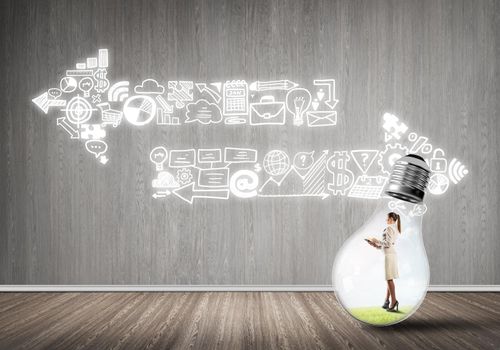 Businesswoman inside of light bulb in empty concrete room