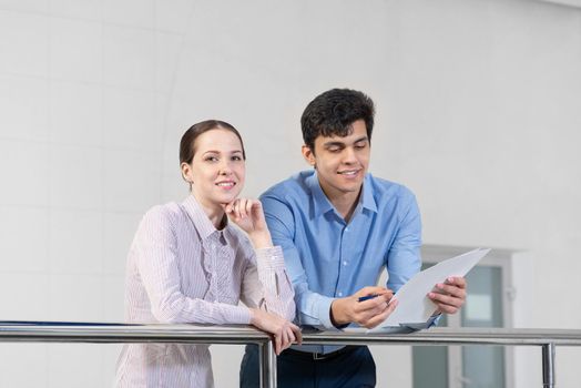 businessman and woman discussing document standing on balcony