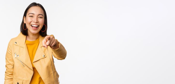 Congratulations, its you. Happy beautiful asian woman laughing, pointing finger at camera, choosing, inviting people, recruiting, standing over white background.