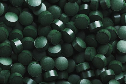 Dark Green round tablets of organic spirulina as a texture background in full screen