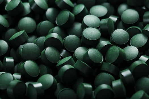 Dark Green round tablets of organic spirulina as a texture background in full screen