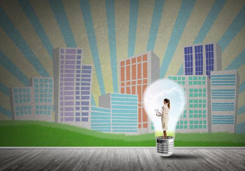 Businesswoman inside light bulb against city drawn concept