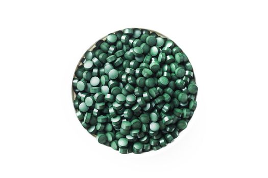 spirulina and chlorella tablets on the light background. green tablets in the small bawl