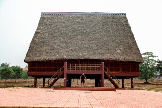 A tourist exploring a traditional architecture of a Bahnar ethnic stilt house or Rong House in Pleiku countryside, Vietnam