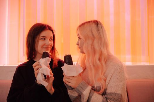 LGBT Lesbian couple eat sushi rolls in asian cafe with red light