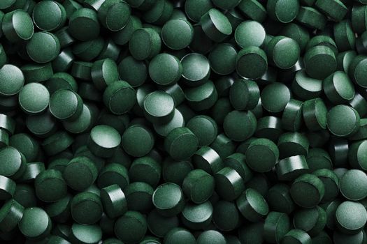 Green tablets from spirulina vegetarian dietary supplement as a full-screen texture