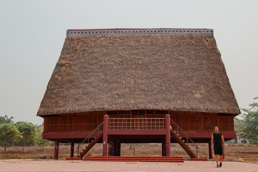 A tourist exploring a traditional architecture of a Bahnar ethnic stilt house or Rong House in Pleiku countryside, Vietnam