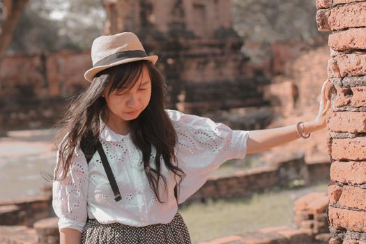 Smiling asian girl exploring the old ruins in Wat Mahathat inside the famous heritage site of Ayutthaya Historical Park in Thailand