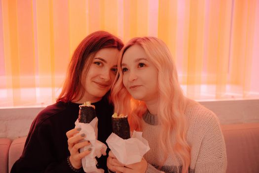 LGBT Lesbian couple eat sushi rolls in asian cafe with red light