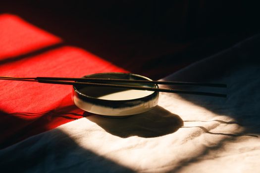 Light and shadows cast on a ceramic incense holder and sticks showing zen, wellness and mindfulness