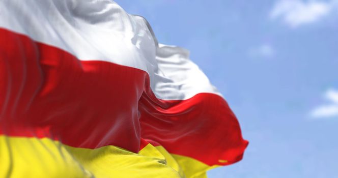 Detail of the national flag of South Ossetia waving in the wind on a clear day. South Ossetia is a breakaway state in the South Caucasus. Selective focus.