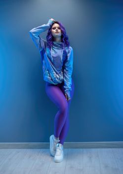 girl in stylish purple sportswear and with purple hair poses sexually