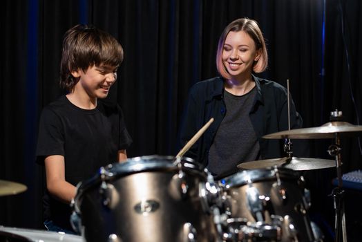 Young woman teaching boy to play drums