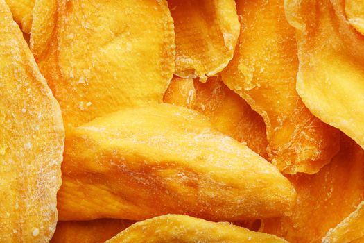 Dried sweet mango fruit slices as textural orange background in full screen