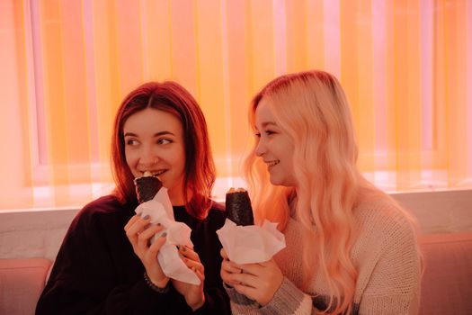 LGBT Lesbian couple eat sushi rolls in asian cafe with red light