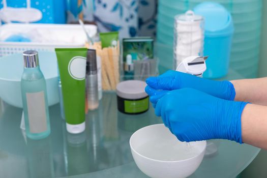 Close up of female cosmetologist hand preparing cotton pad for facial deep cleansing procedure