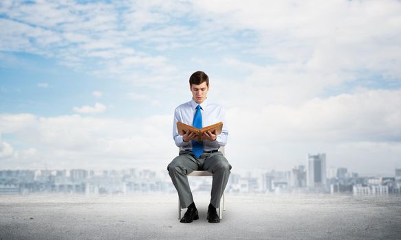 young businessman with book on office chair