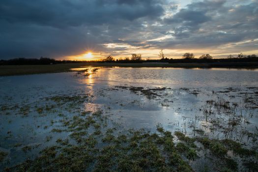 Clouds and sunset over the flooded and frozen meadow, spring evening