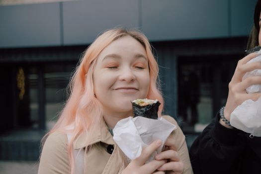 LGBT Lesbian woman eat sushi rolls on the walk asian cafe. street food