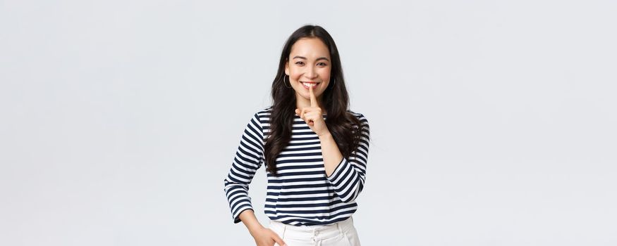 Lifestyle, people emotions and casual concept. Smiling cute asian girl asking keep secret, take promise not tell or be quiet about it, show shush sign, hush with finger over mouth.
