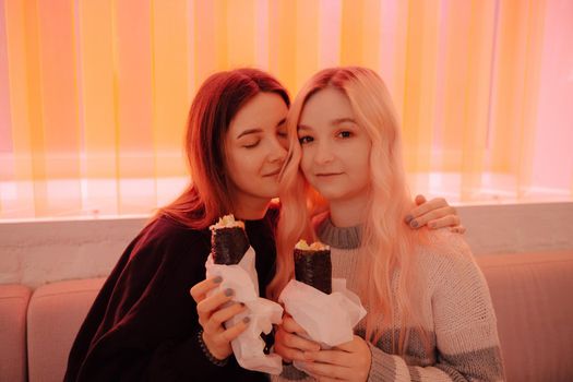 LGBT Lesbian couple eat sushi rolls in asian cafe with red light