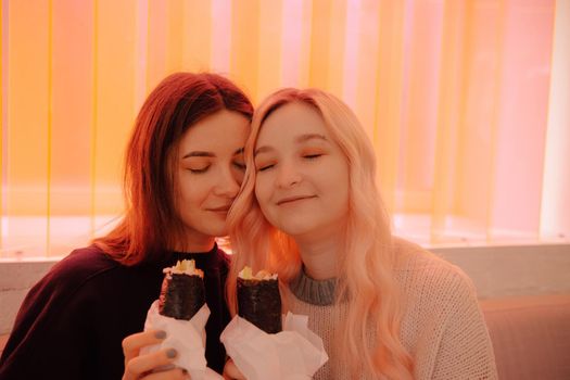 LGBT Lesbian couple eat sushi rolls in asian cafe with red light