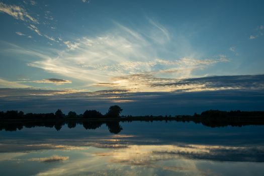 Reflection of clouds in the lake water, summer evening