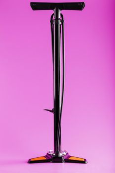 Black bicycle manual air pump for pumping wheels on a pink background with a vertical composition