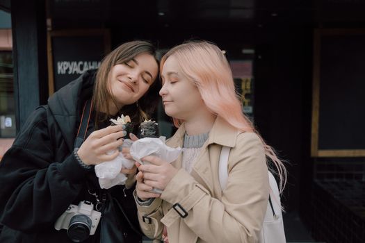 LGBT Lesbian couple eat sushi rolls on the walk asian cafe. street food concept