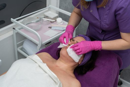 The beautician gently rubs the exfoliating preparation all over the skin of the face