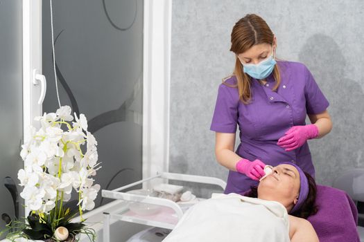 After washing the face with the gel, the beautician wipes dry the remains of the wet gel from the client's face.